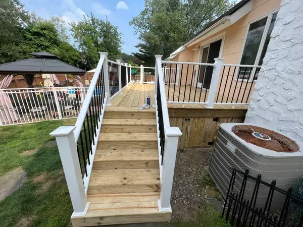 A wooden deck with stairs leading up to it next to a house.