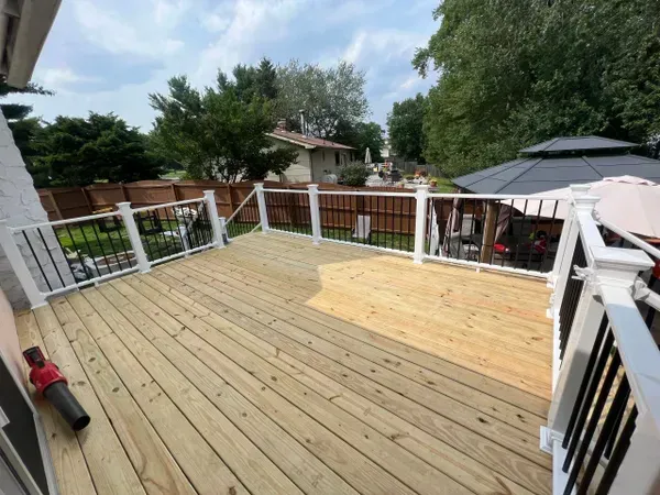 A wooden deck with a white railing and a gazebo in the background.