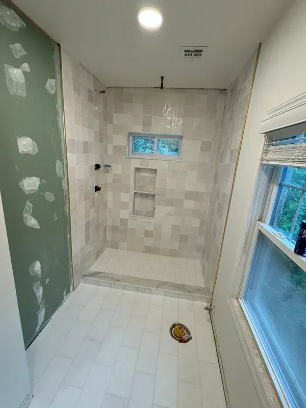 A bathroom with a walk in shower and a window.