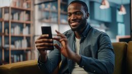 A man is sitting on a couch using a cell phone.