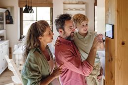 A family is looking at a smart thermostat in their home.