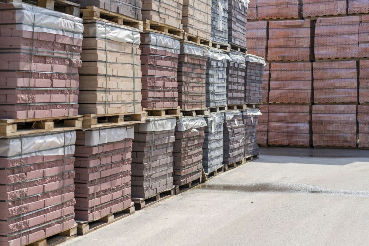 Pile di pallet di mattoni rosa e grigi in un deposito all'aperto