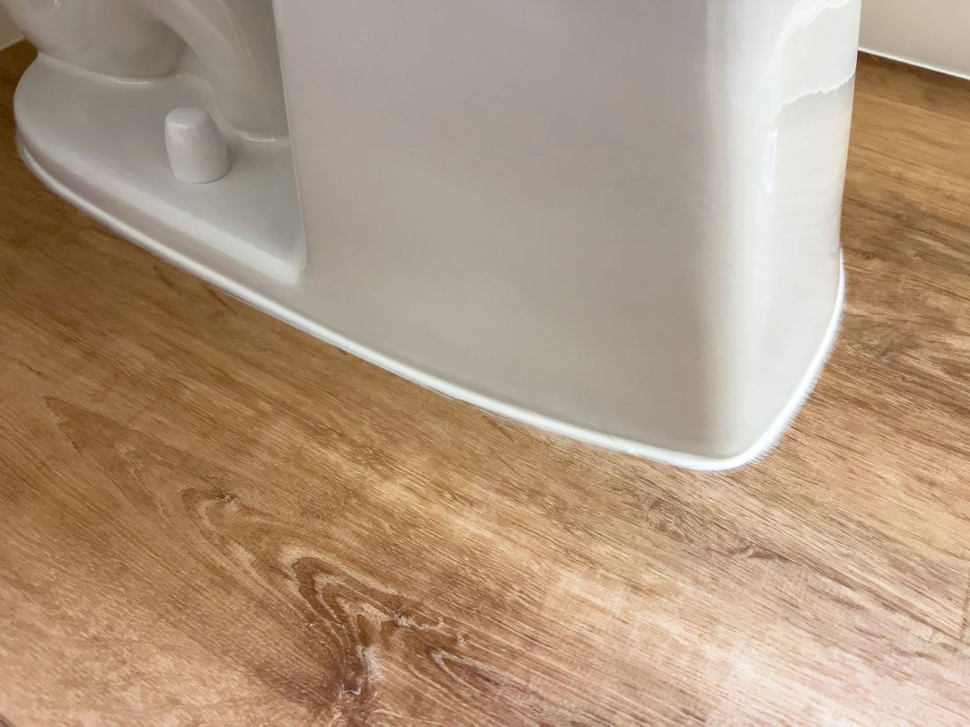 Primo piano di un angolo bianco di un elettrodomestico su un pavimento di legno.