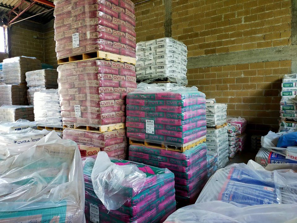 Pile di pallet imballati in un magazzino, con imballaggi rosa e bianchi contro un muro di mattoni.