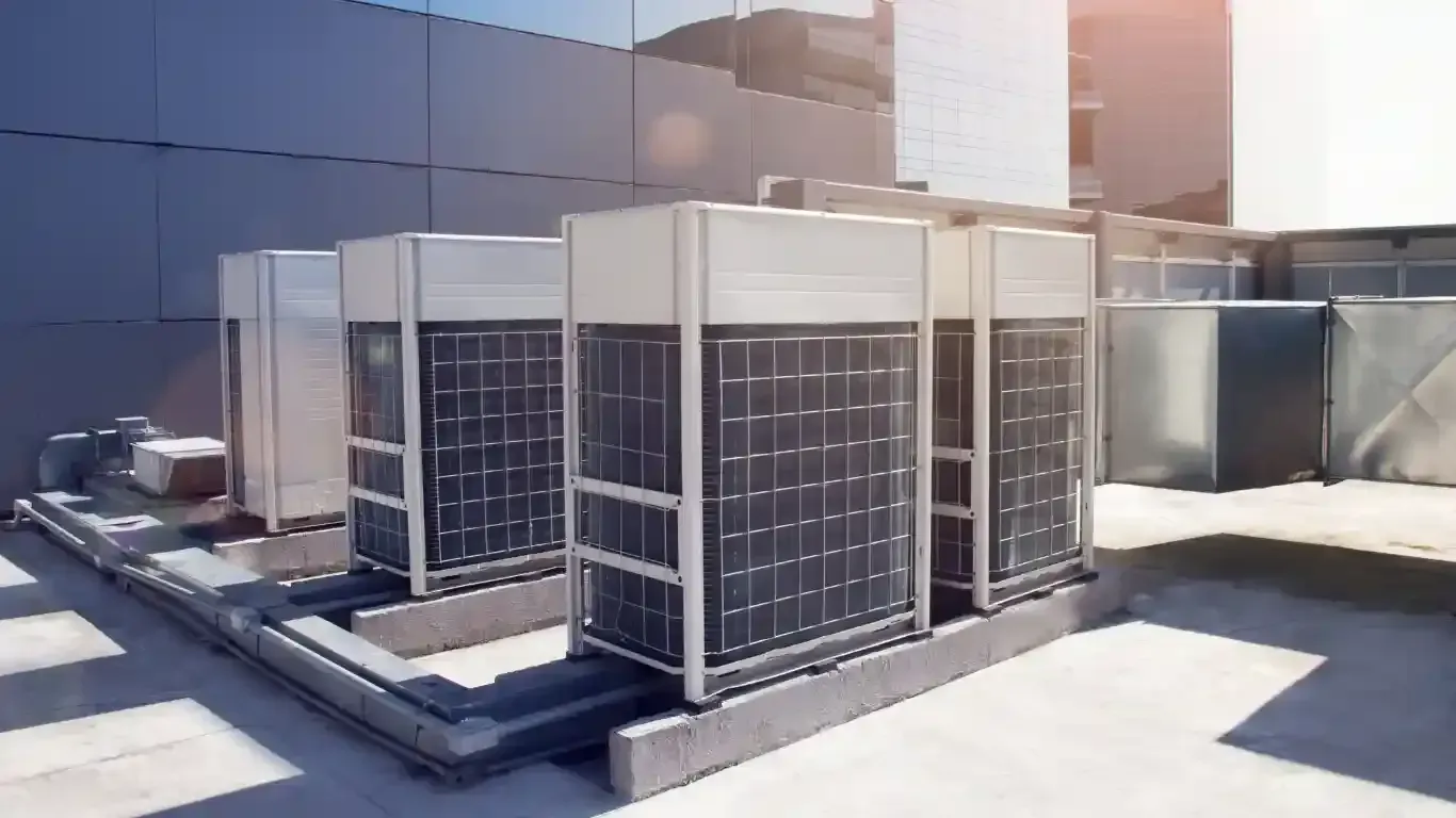 HVAC technician working on an air conditioning unit on a rooftop.