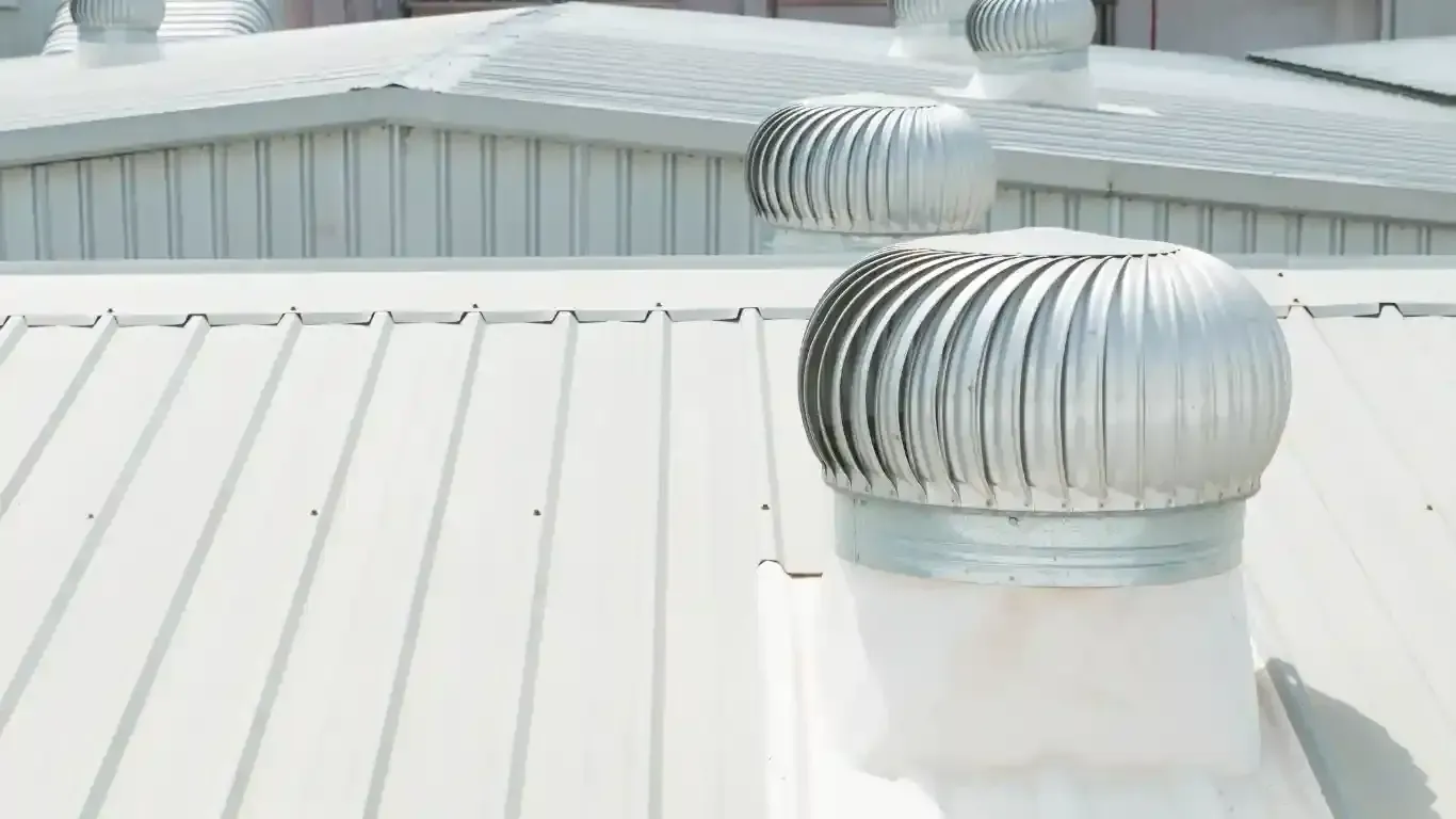 HVAC technician inspecting ventilation system, surrounded by insulated ductwork and metal components.
