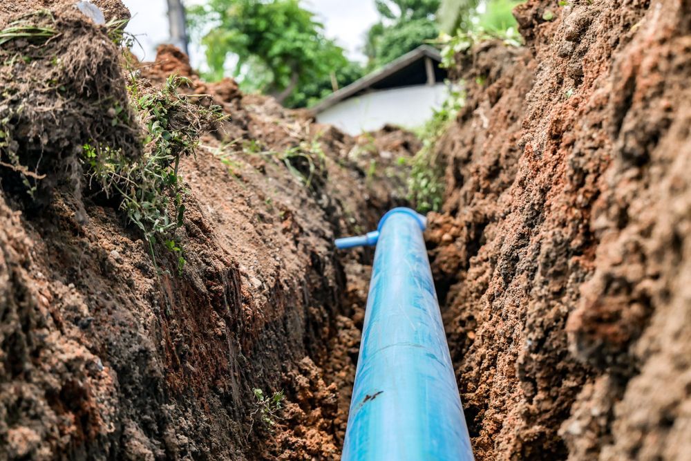 A blue pipe is being installed in a trench.