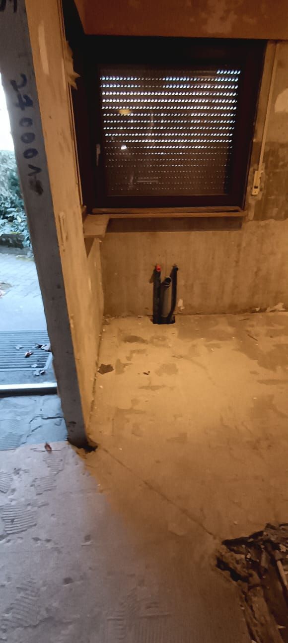 A room with a door open and a window with a shutter on it.