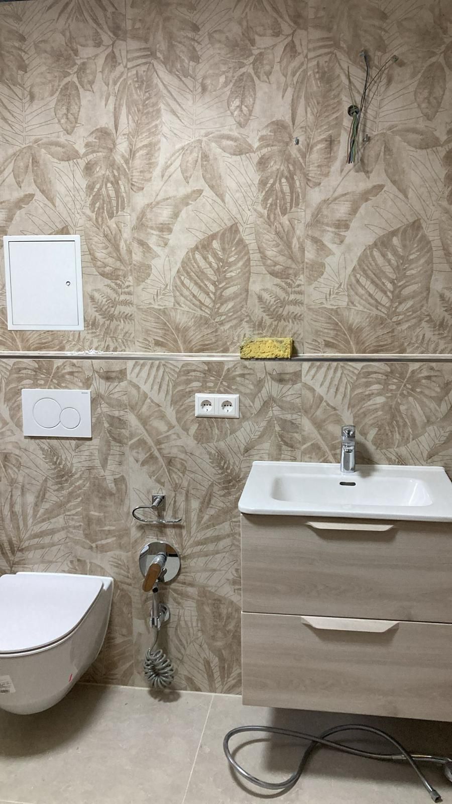 A bathroom with a toilet , sink , and drawers.