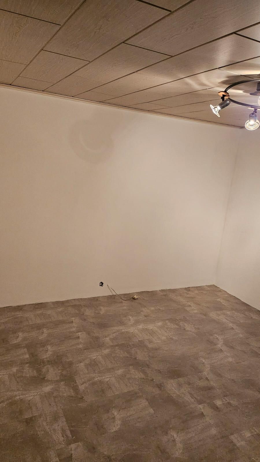 An empty room with a ceiling fan and a white wall.
