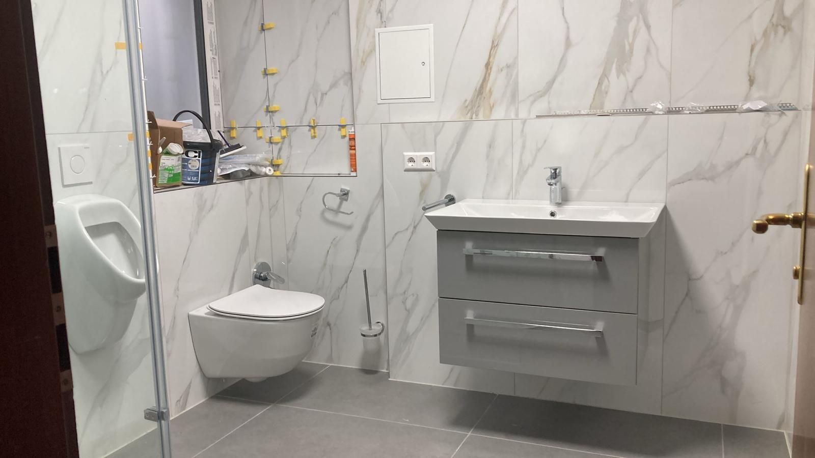 A bathroom with a toilet , sink and urinal.