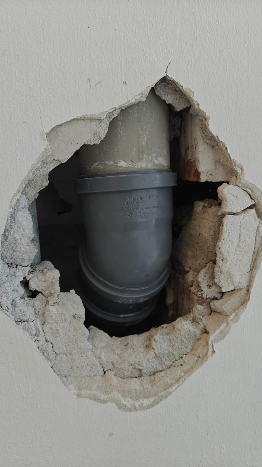 A pipe is coming out of a hole in a wall.