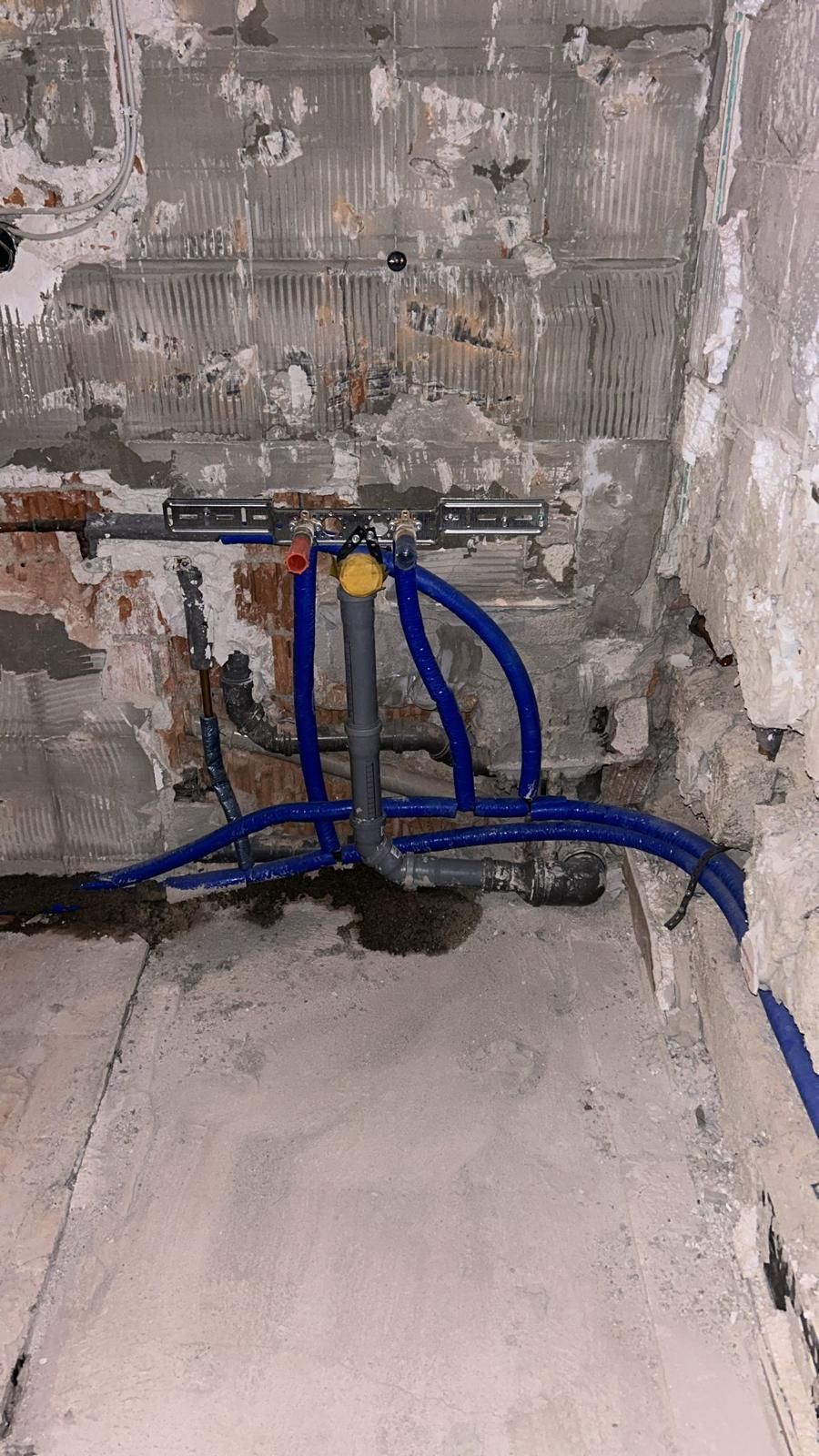 A bathroom with a lot of pipes coming out of the wall.