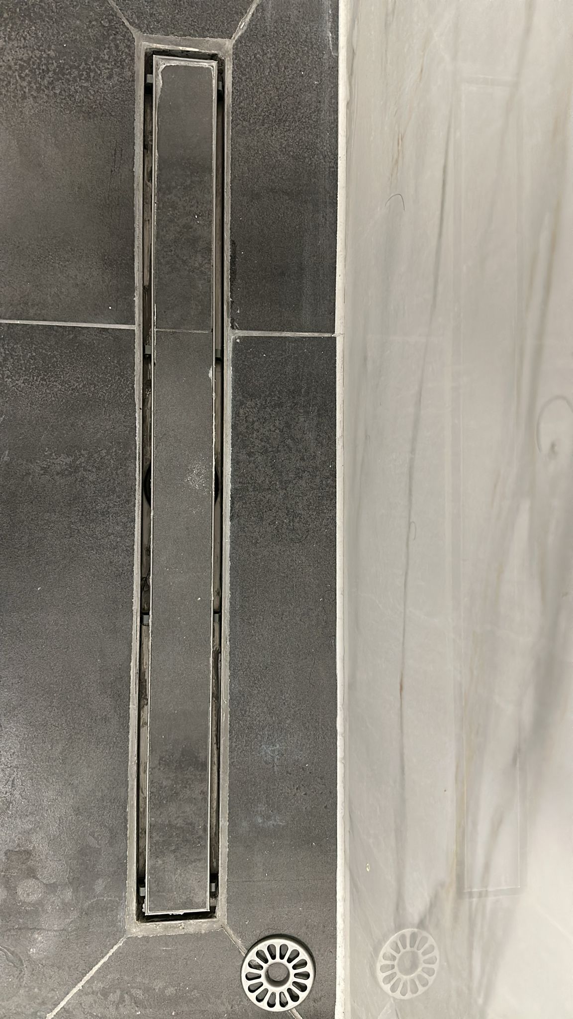 A black and white photo of a shower drain in a bathroom.
