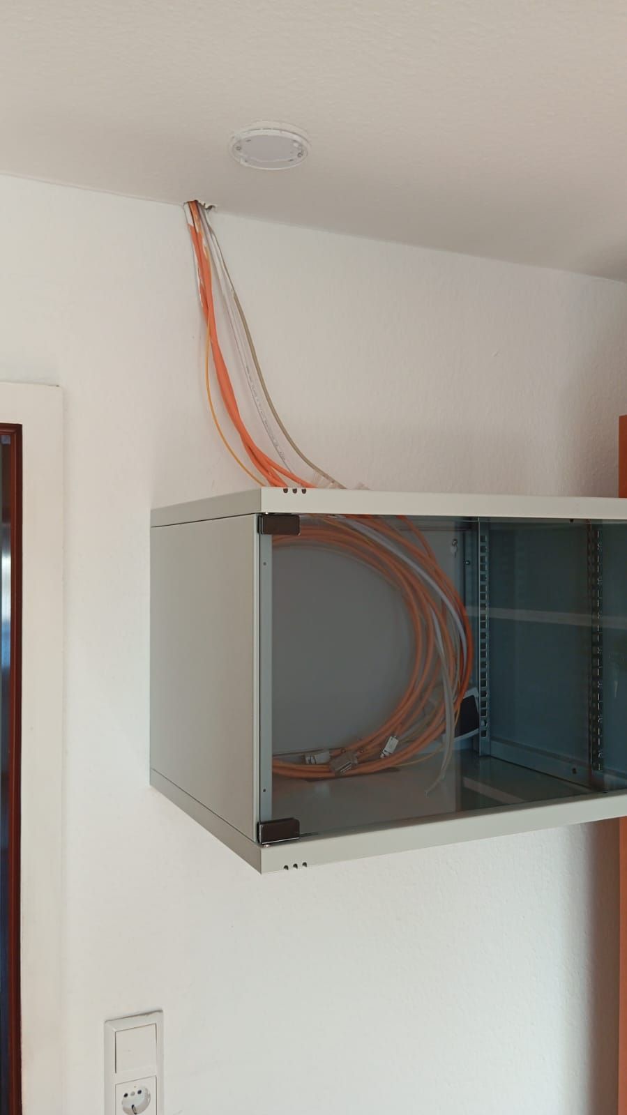 A wall mounted cabinet with a bunch of wires coming out of it.