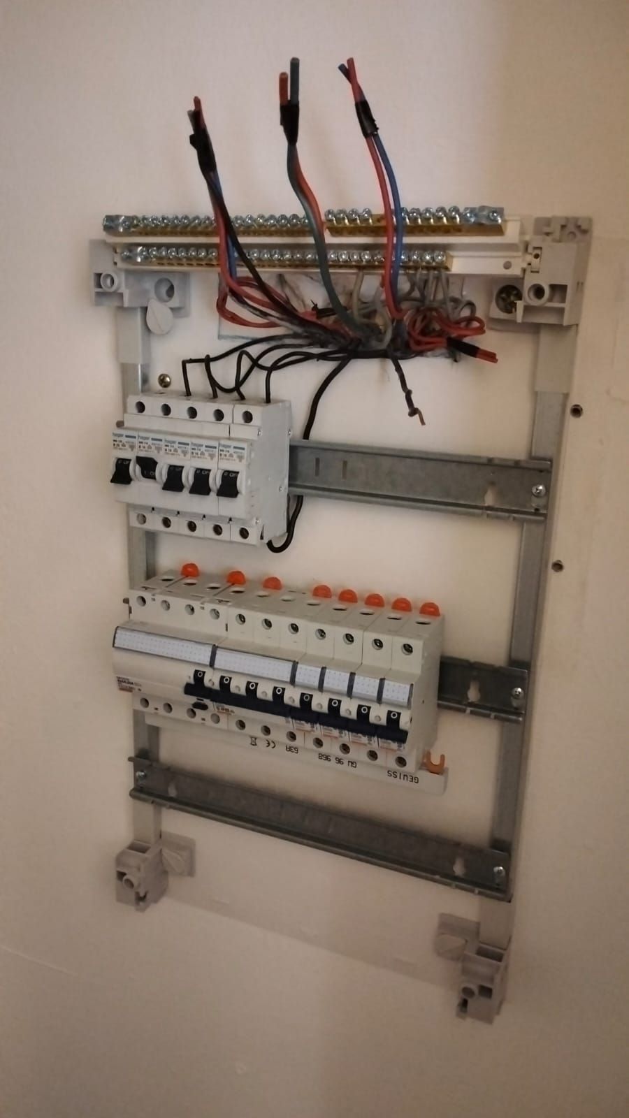 Electrical panel mounted on a white wall, containing circuit breakers and wiring.