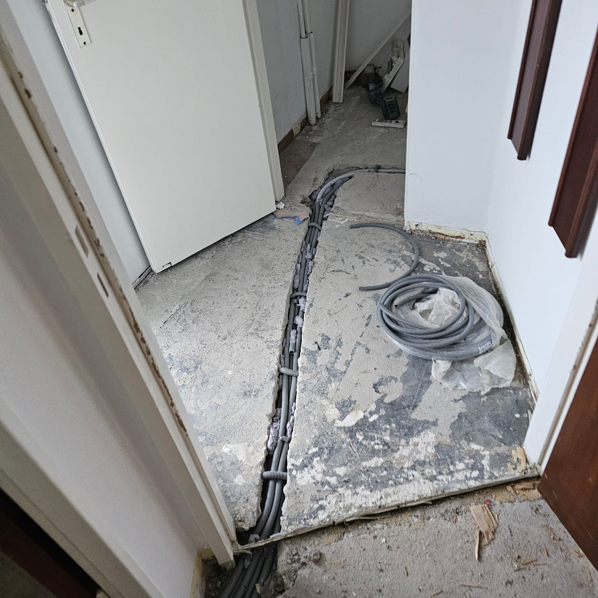 Hallway with exposed cables on concrete floor, doorway visible on each side.