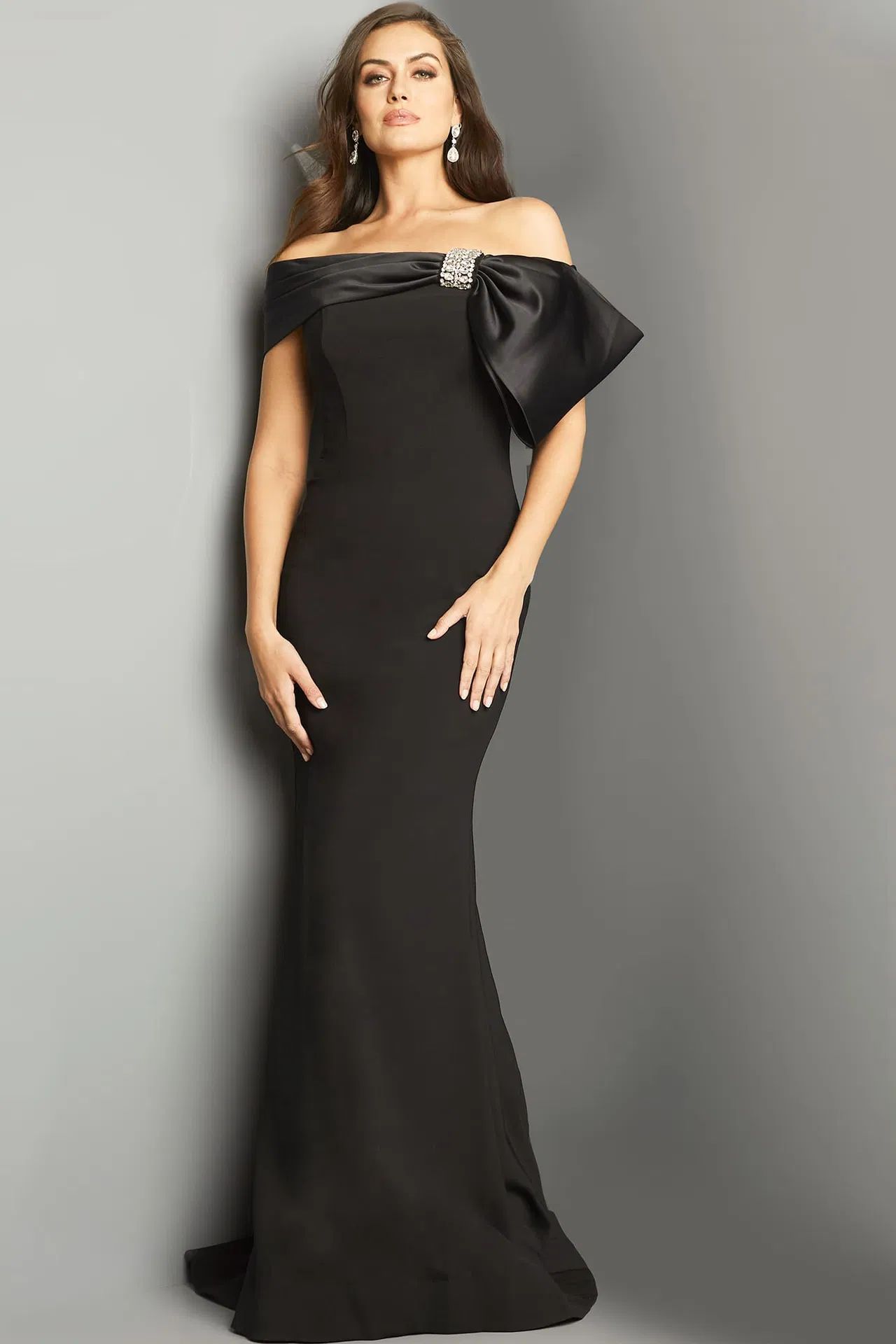 A woman is wearing a black off the shoulder dress with a bow.