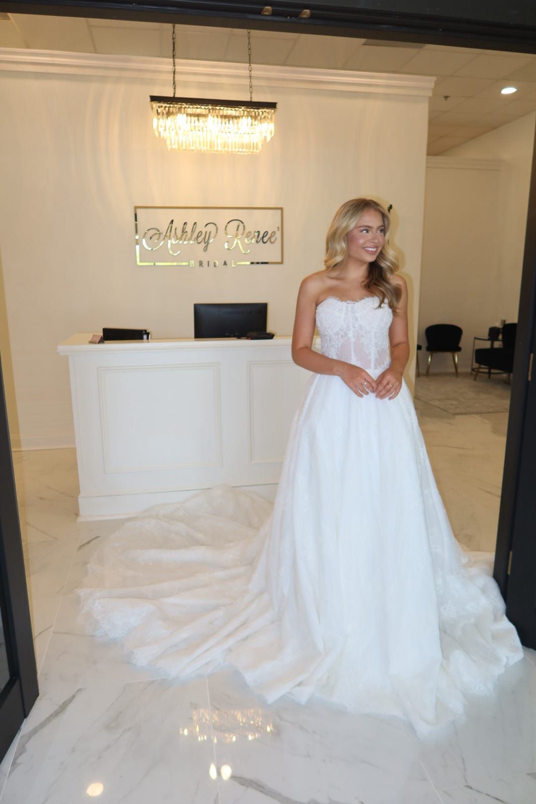 A woman in a white wedding dress is standing in front of a reception desk.