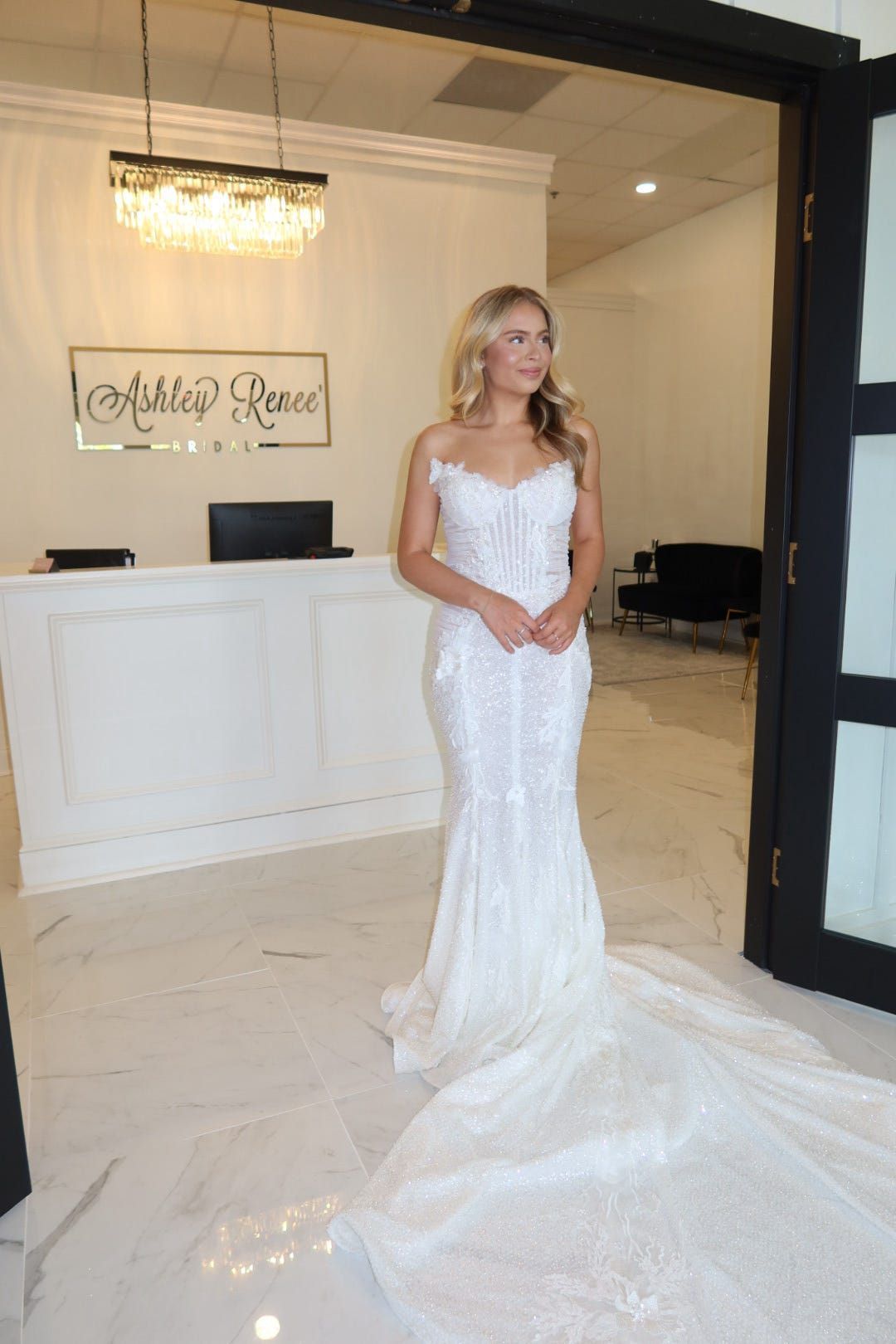 A woman in a white wedding dress is standing in a room.