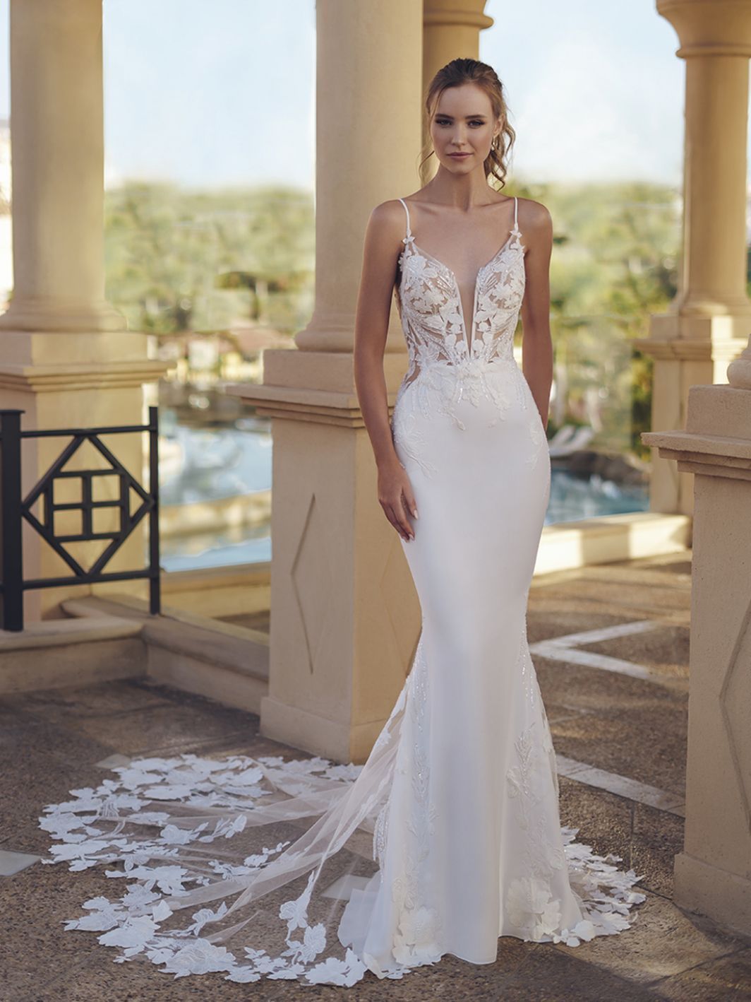 A woman in a white wedding dress is standing in front of a pool.