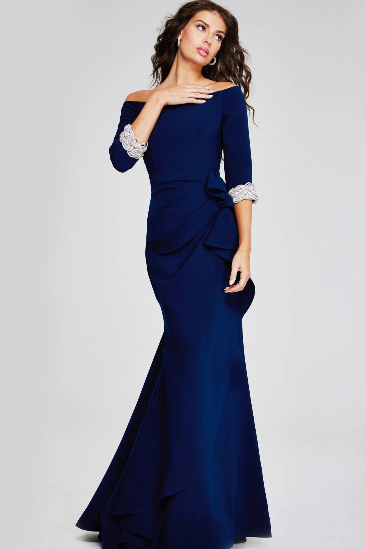 A woman is wearing a long blue dress with pearls on the sleeves.