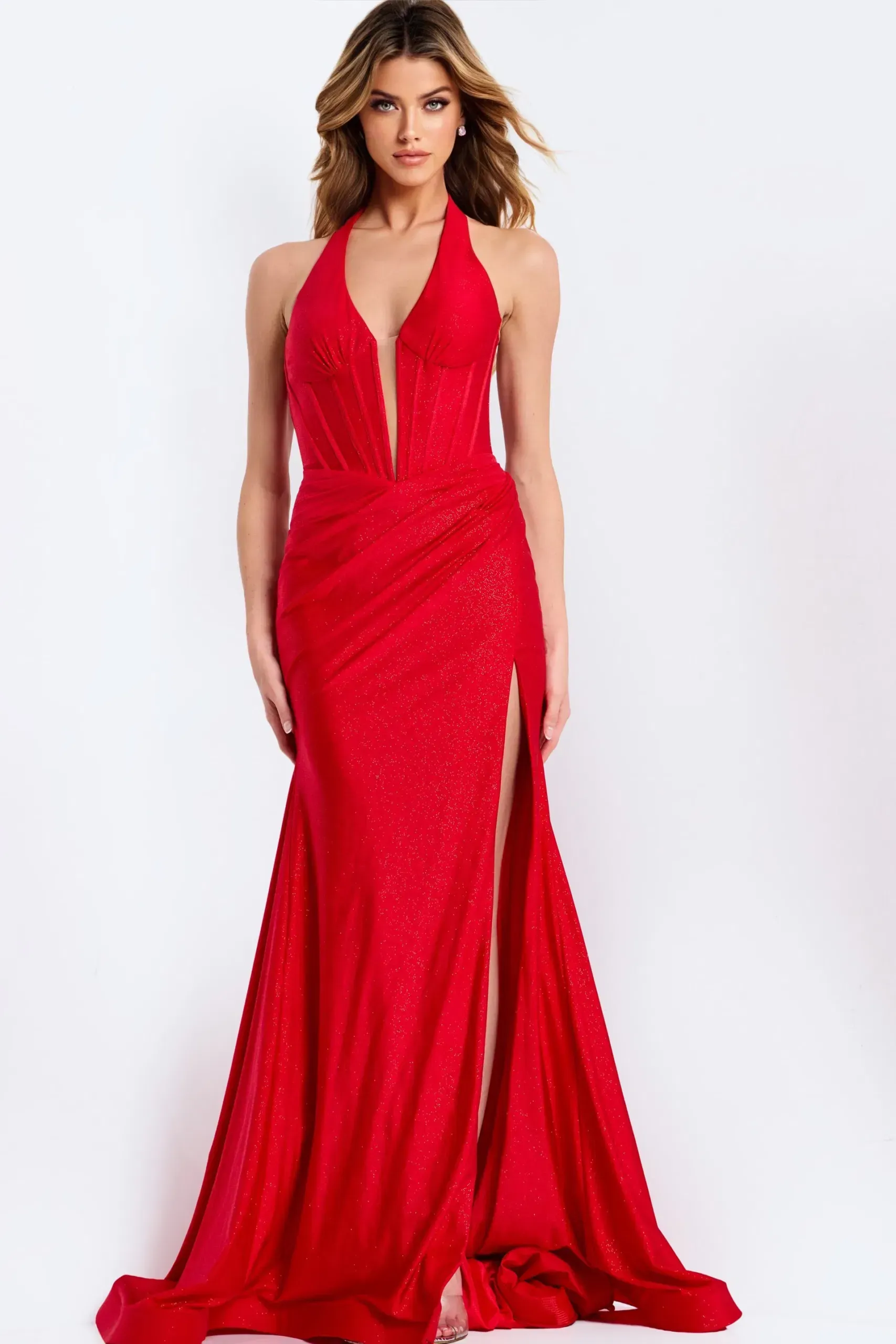 Woman in red halter gown with a thigh-high slit, posing in a studio.