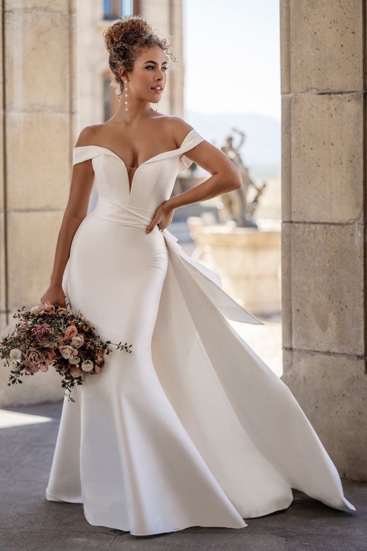 A woman in a white wedding dress is holding a bouquet of flowers.