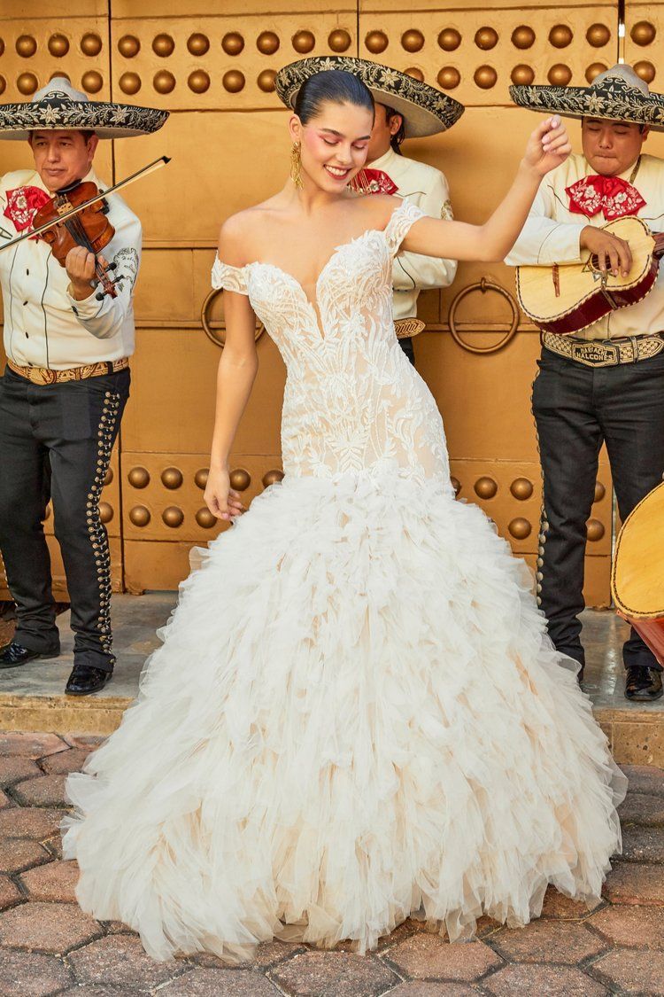 A woman in a white dress is dancing in front of mariachi players
