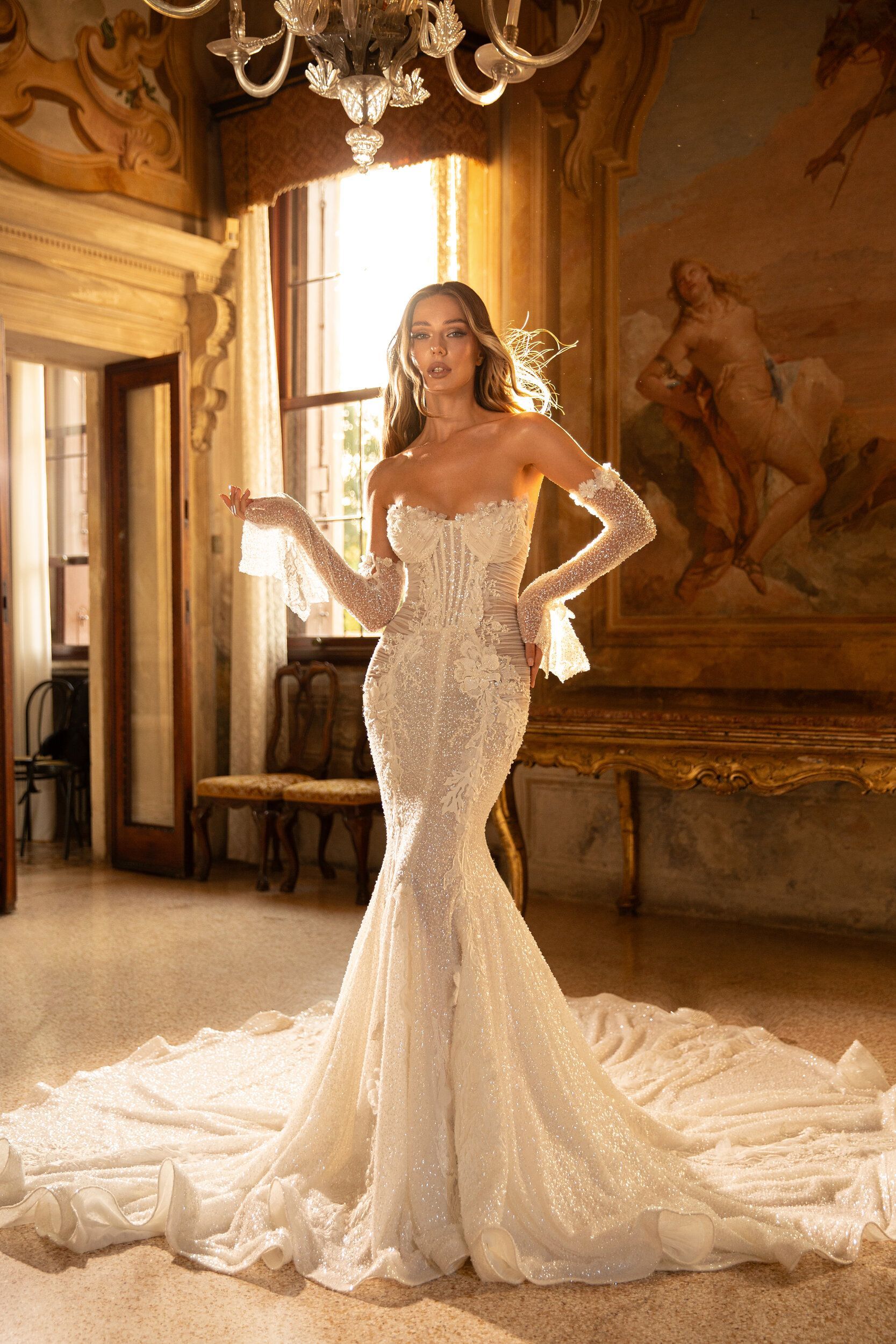 A woman in a wedding dress and gloves is standing in a room.