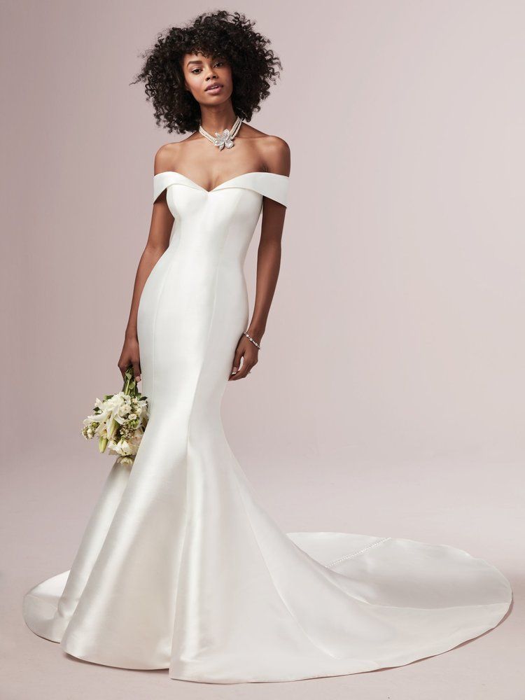 A woman in a white wedding dress is holding a bouquet of flowers.
