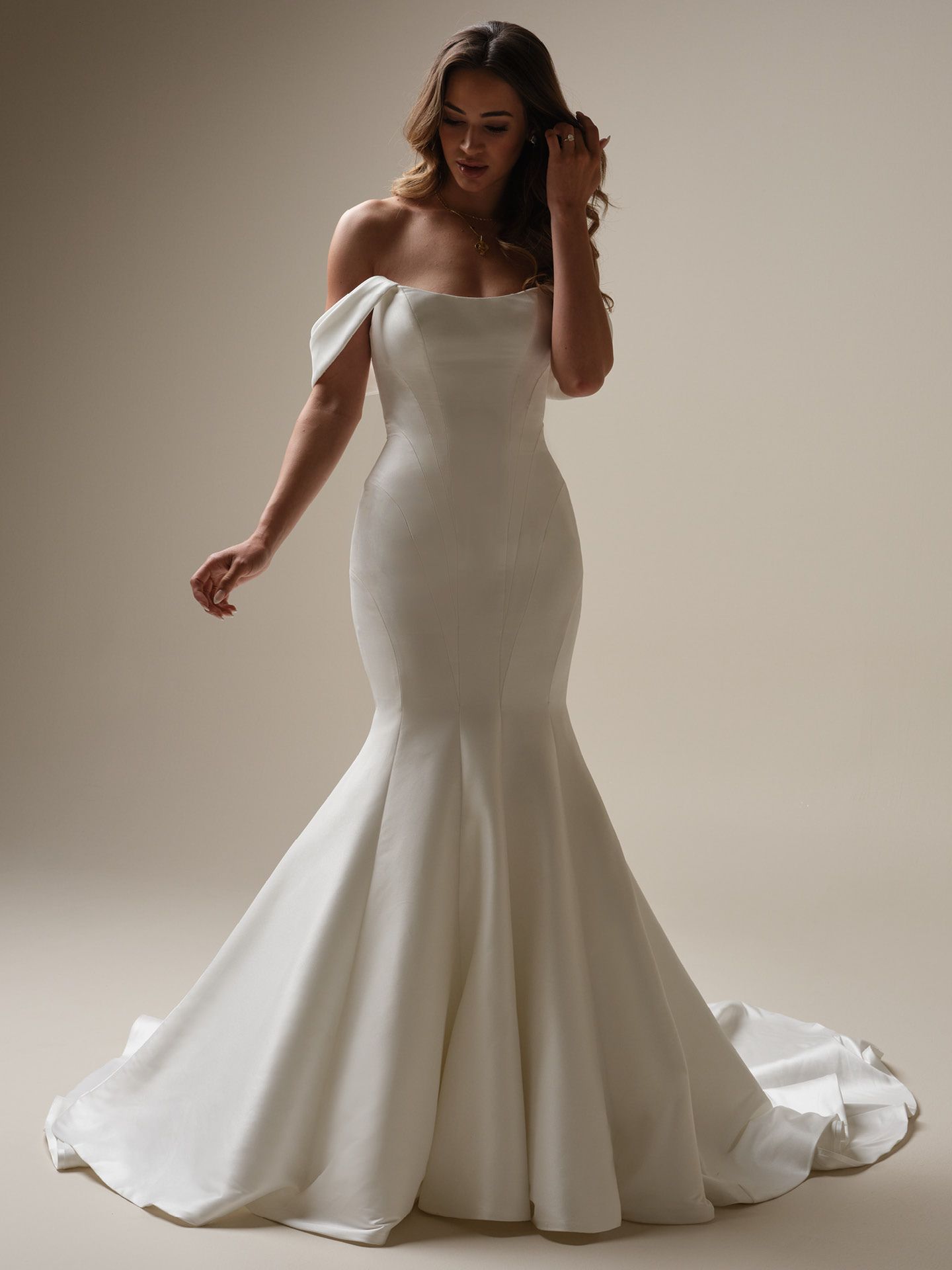 A woman is wearing a white off the shoulder wedding dress.