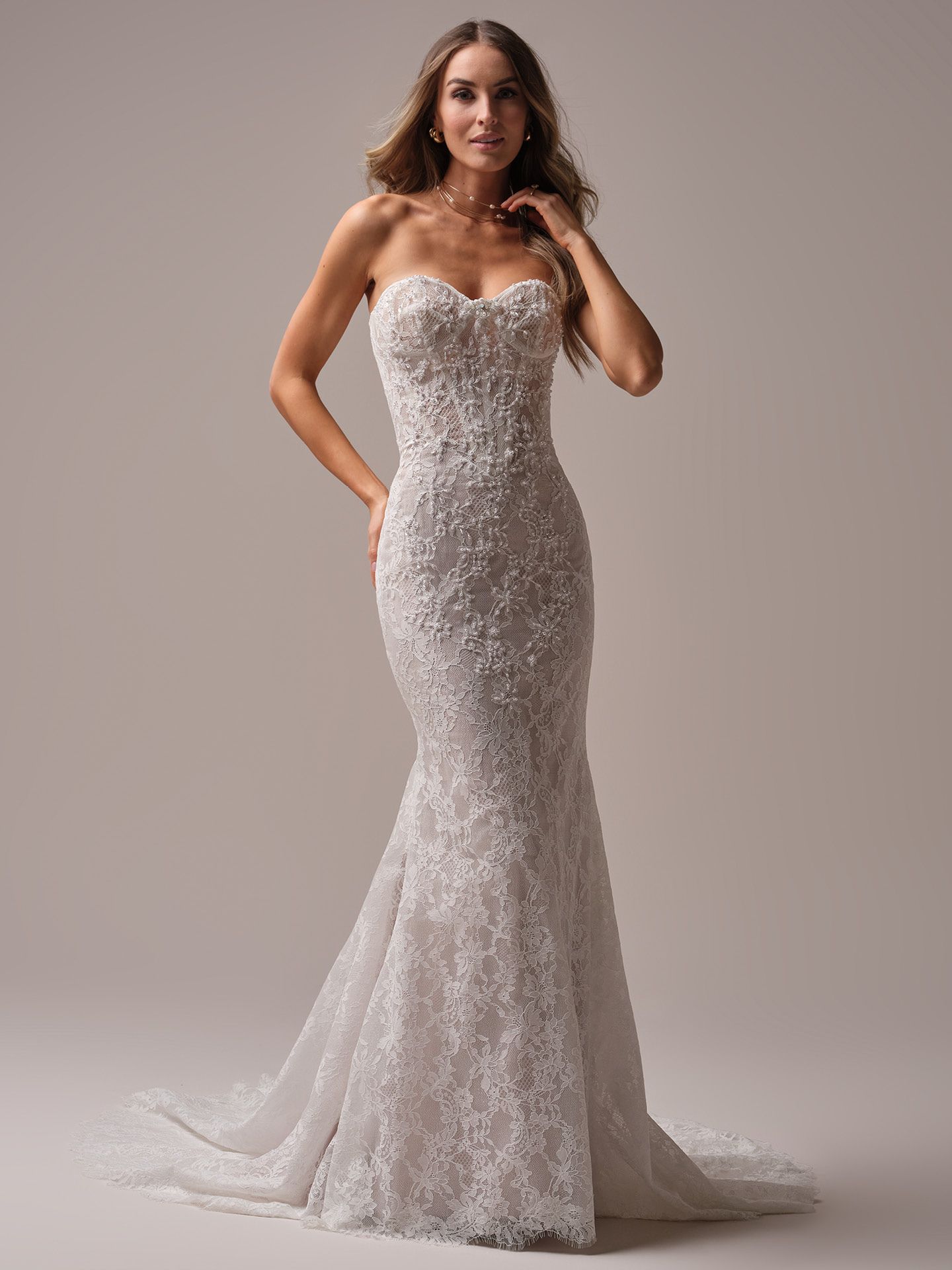 Woman in a white, strapless, mermaid-style wedding dress, posing indoors.