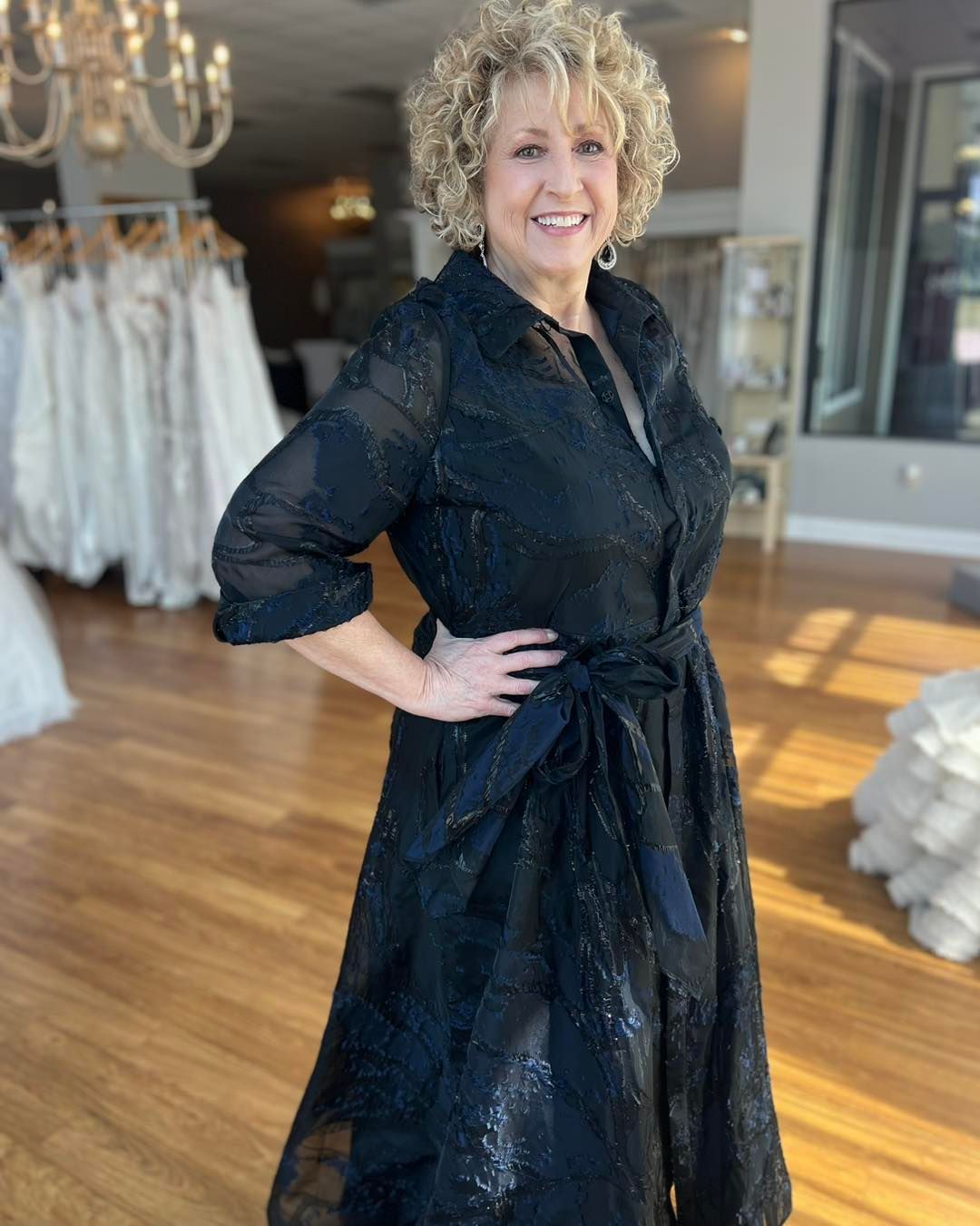 A woman in a black dress is standing in a bridal shop.