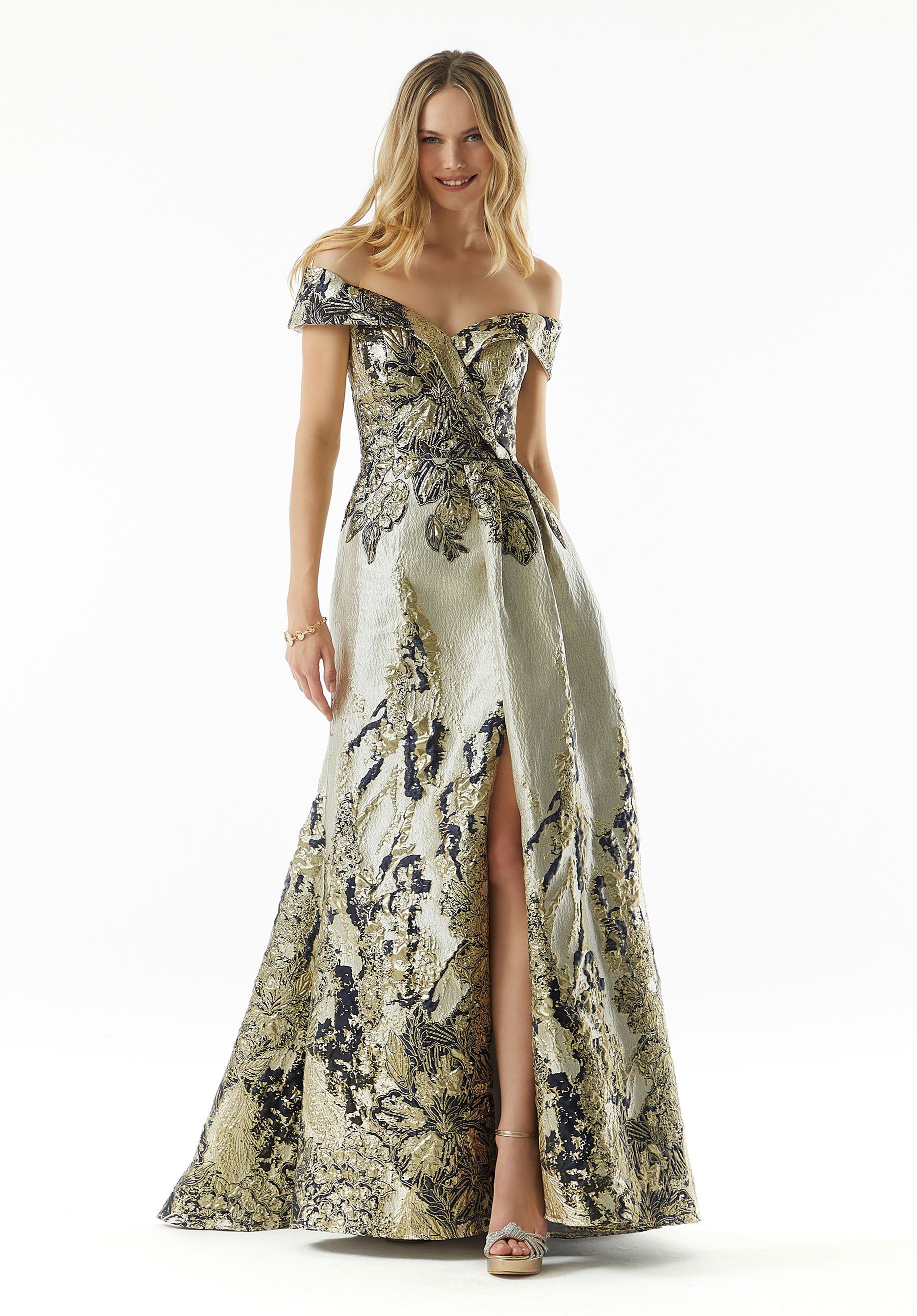 A woman is wearing a long gold and black dress with a high slit.