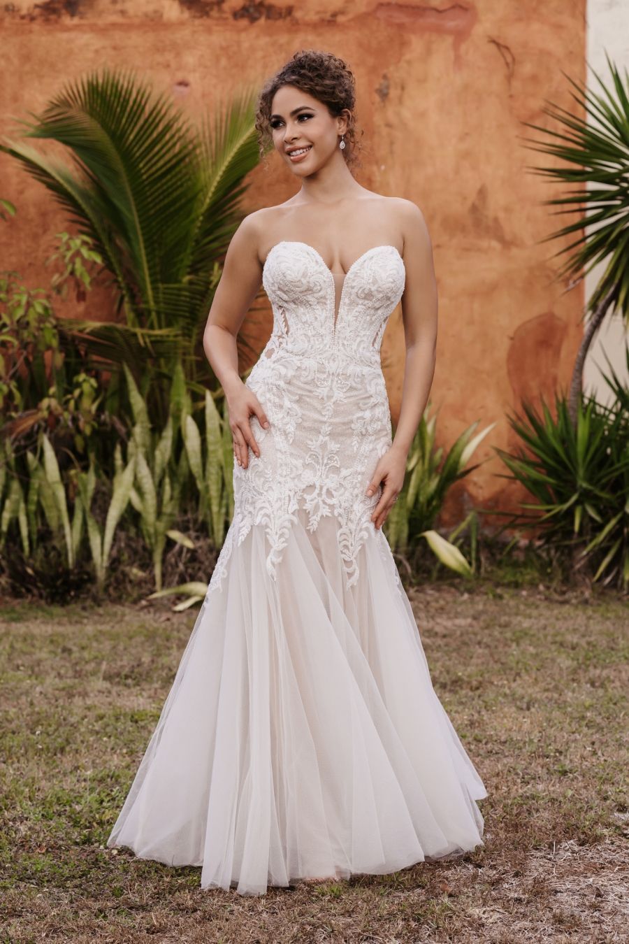 A woman in a white wedding dress is standing in the grass.