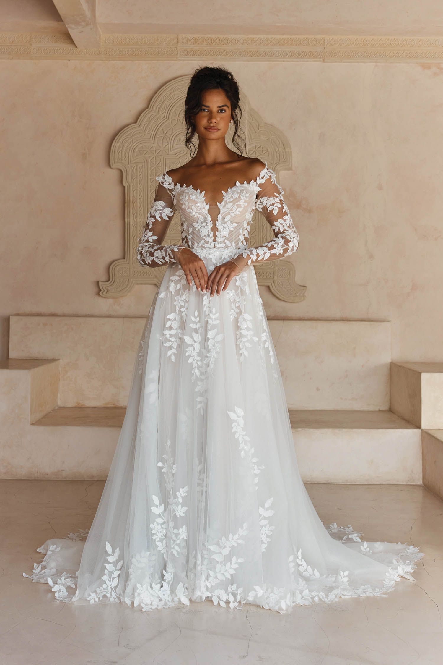 A woman is wearing a white wedding dress with long sleeves.