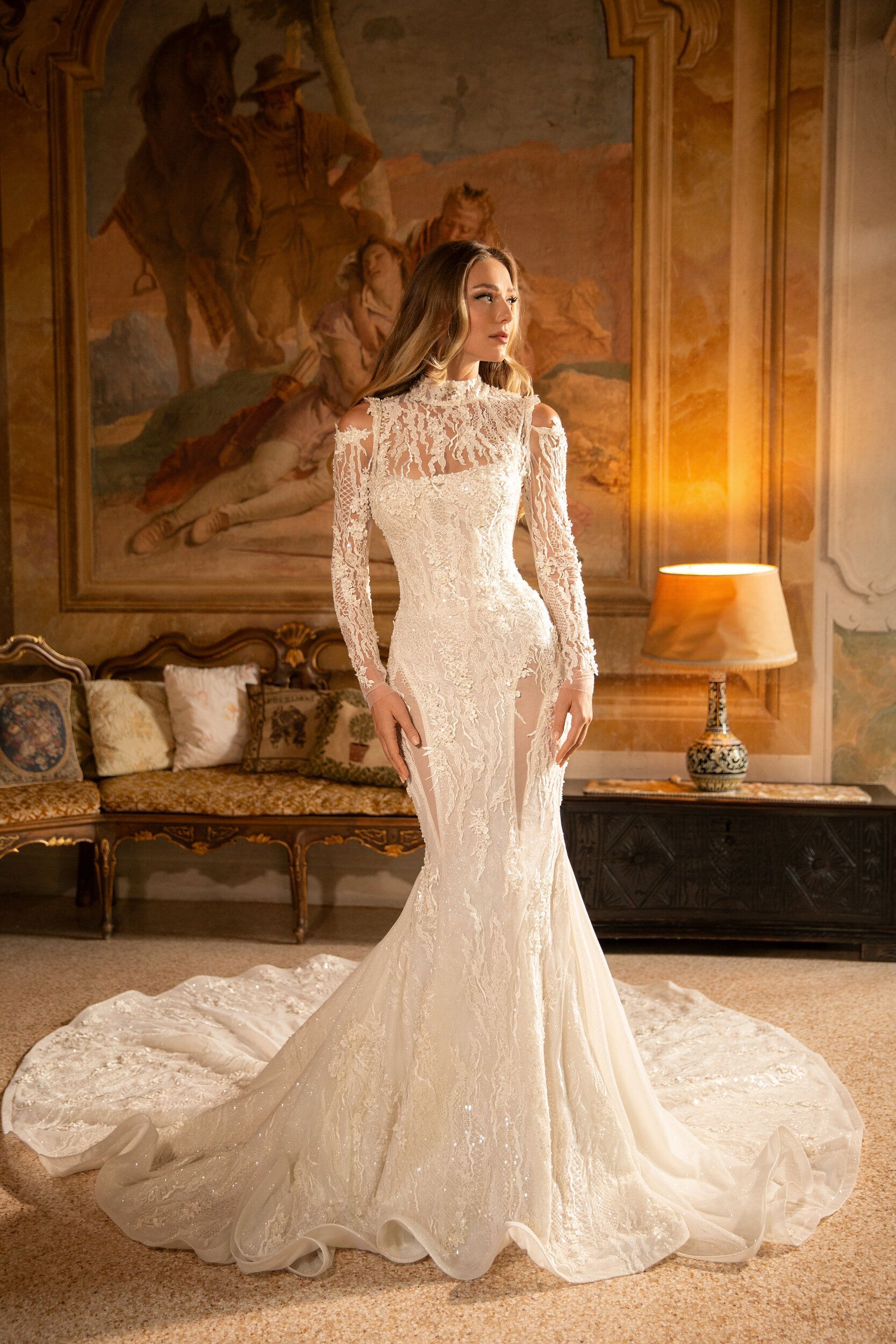 A woman in a wedding dress is standing in a room in front of a painting.