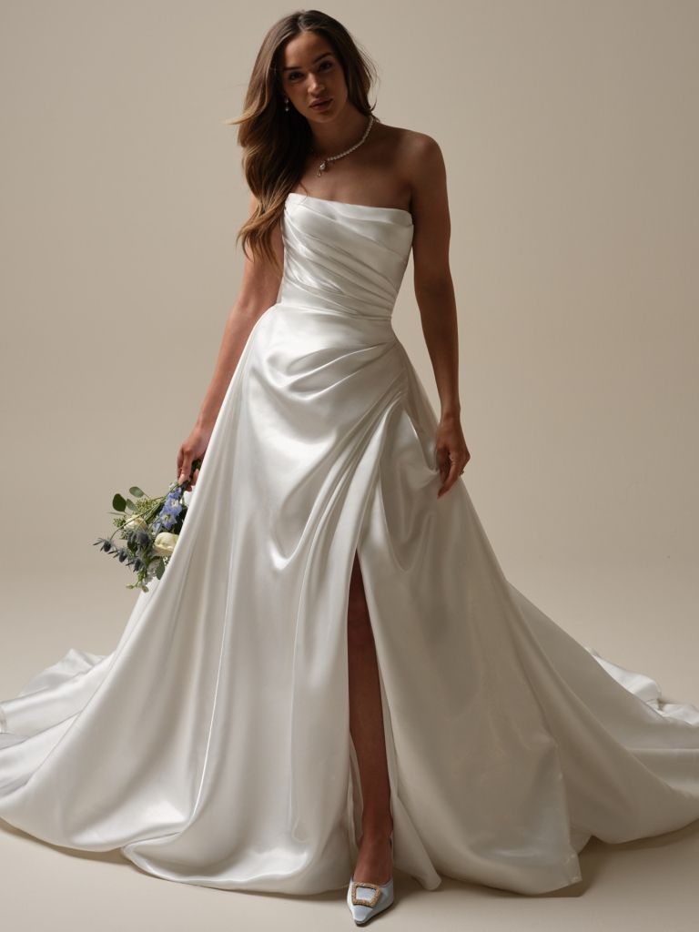 A woman in a white wedding dress is holding a bouquet of flowers.