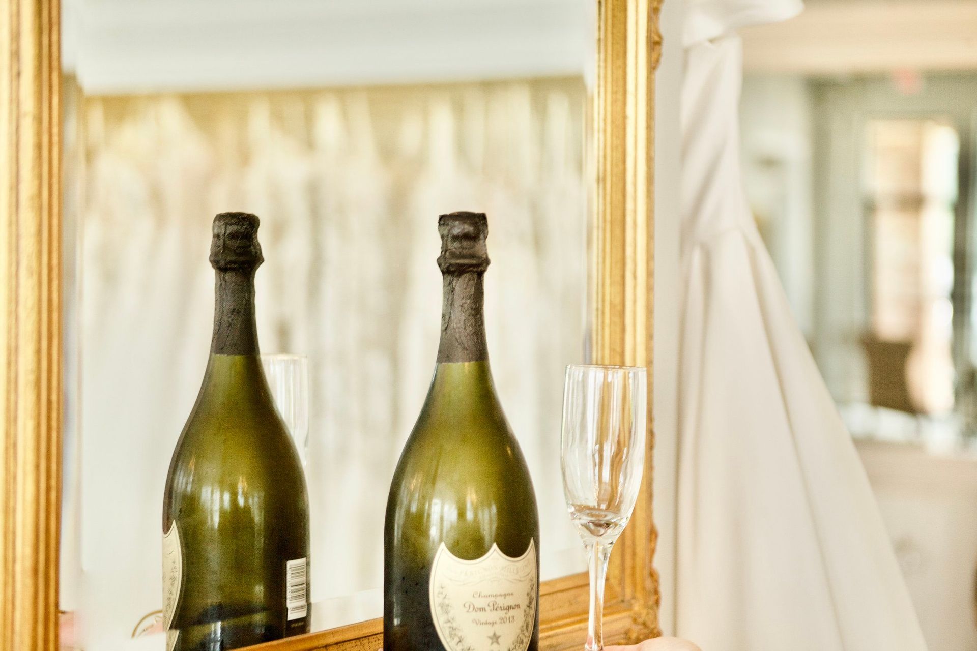 Two bottles of champagne are sitting in front of a mirror.