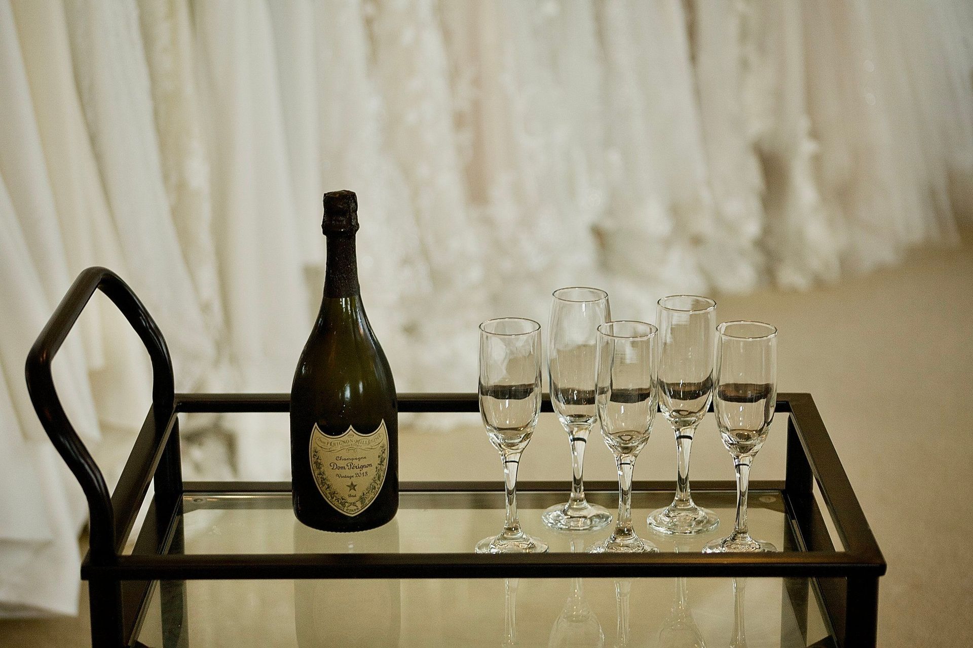 A bottle of champagne is sitting on a glass tray next to glasses.