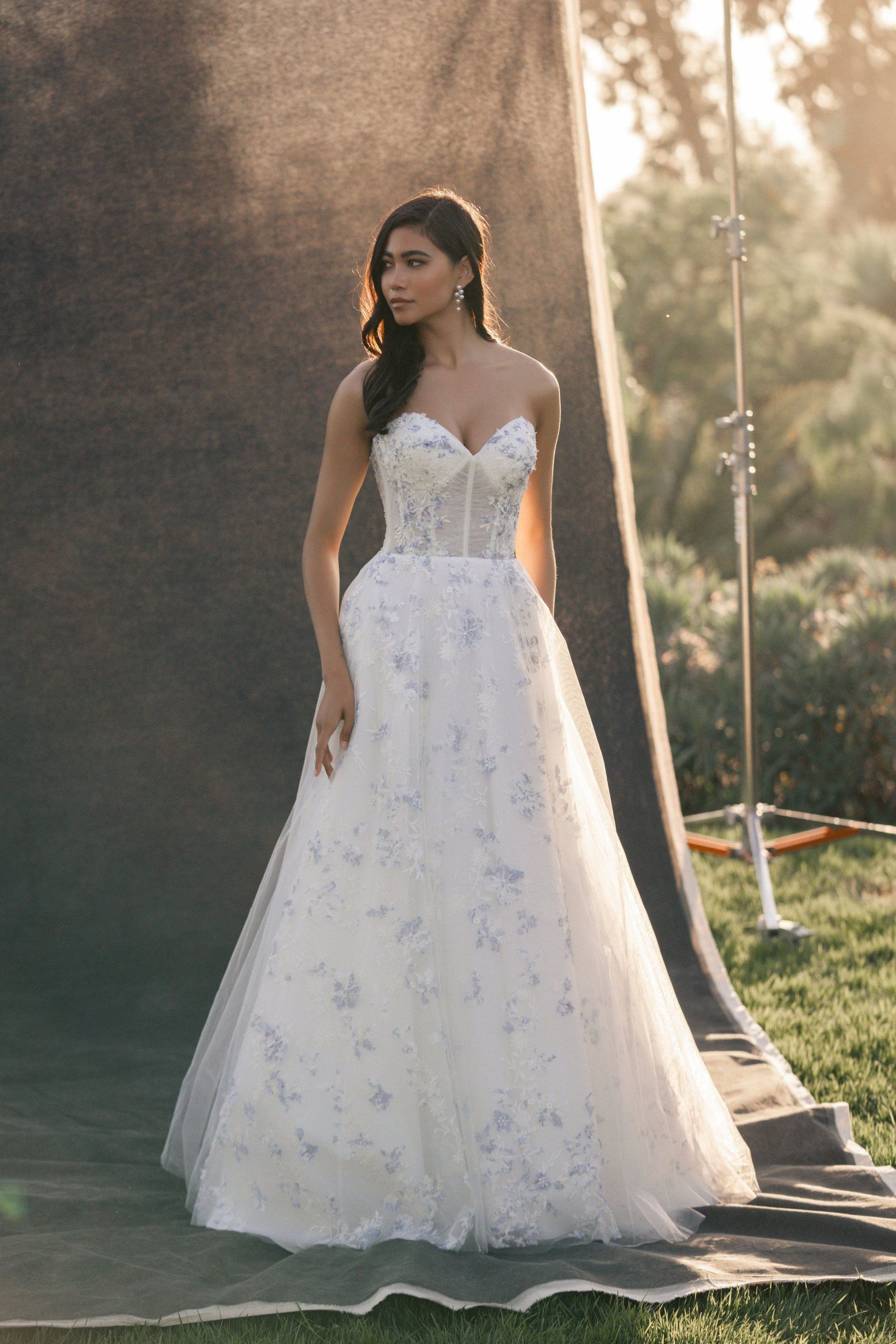 A woman in a white wedding dress is standing in a field.