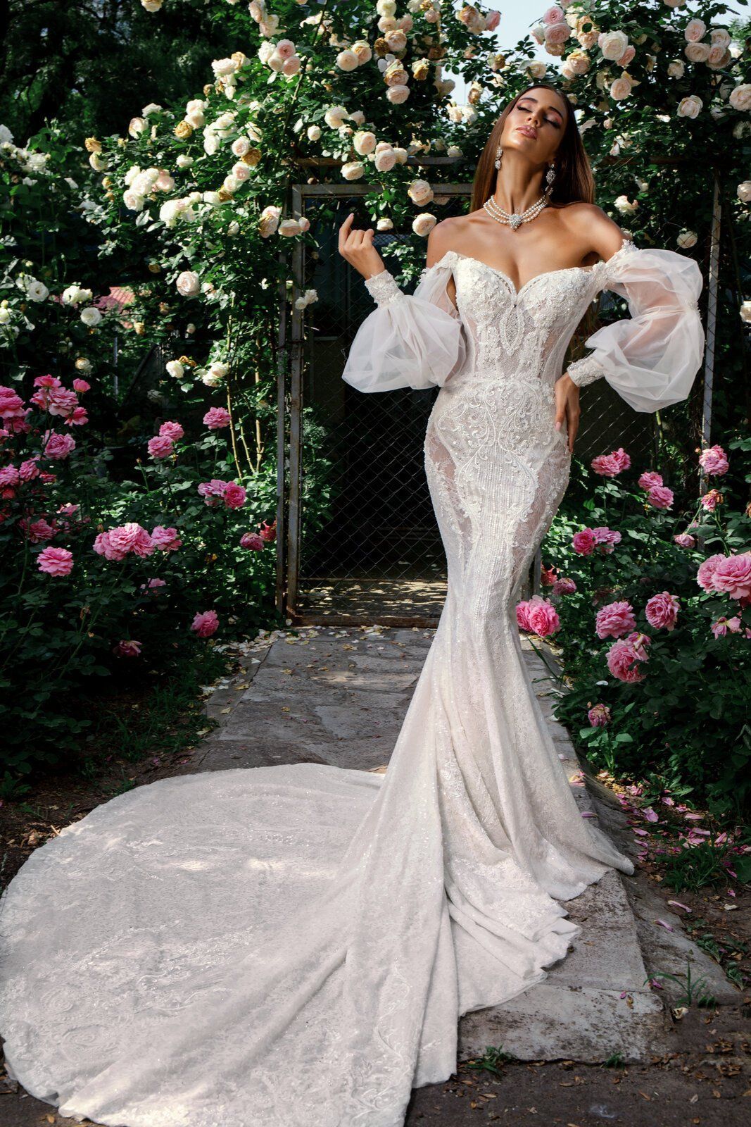 A woman in a wedding dress is standing in a garden surrounded by flowers.