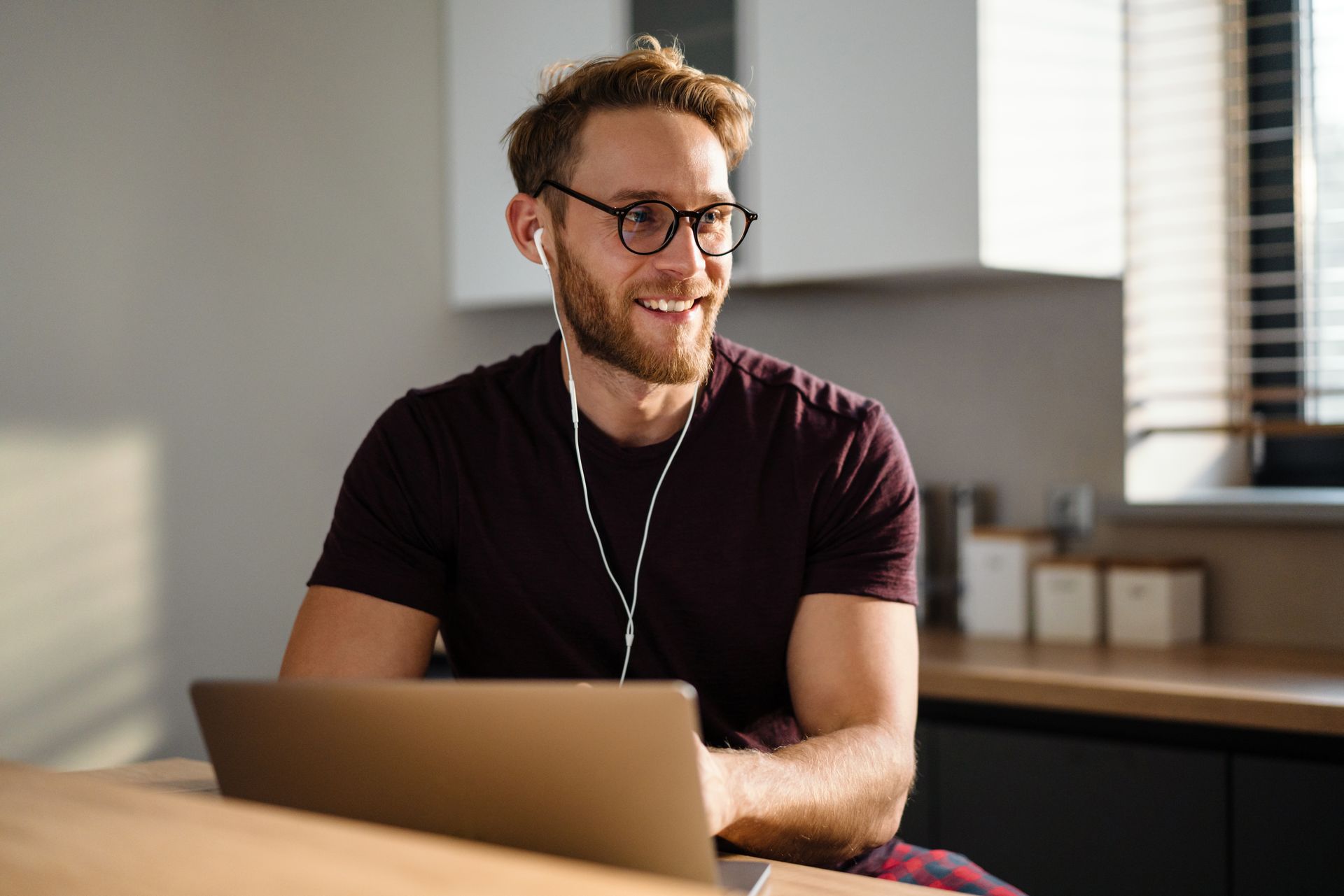 A man is sitting at a table with a laptop and headphones on.