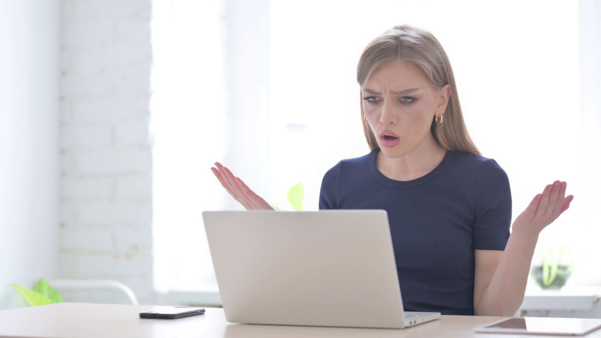 A woman is sitting at a desk using a laptop computer.