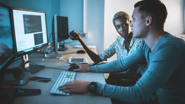A man and a woman are looking at a computer screen.