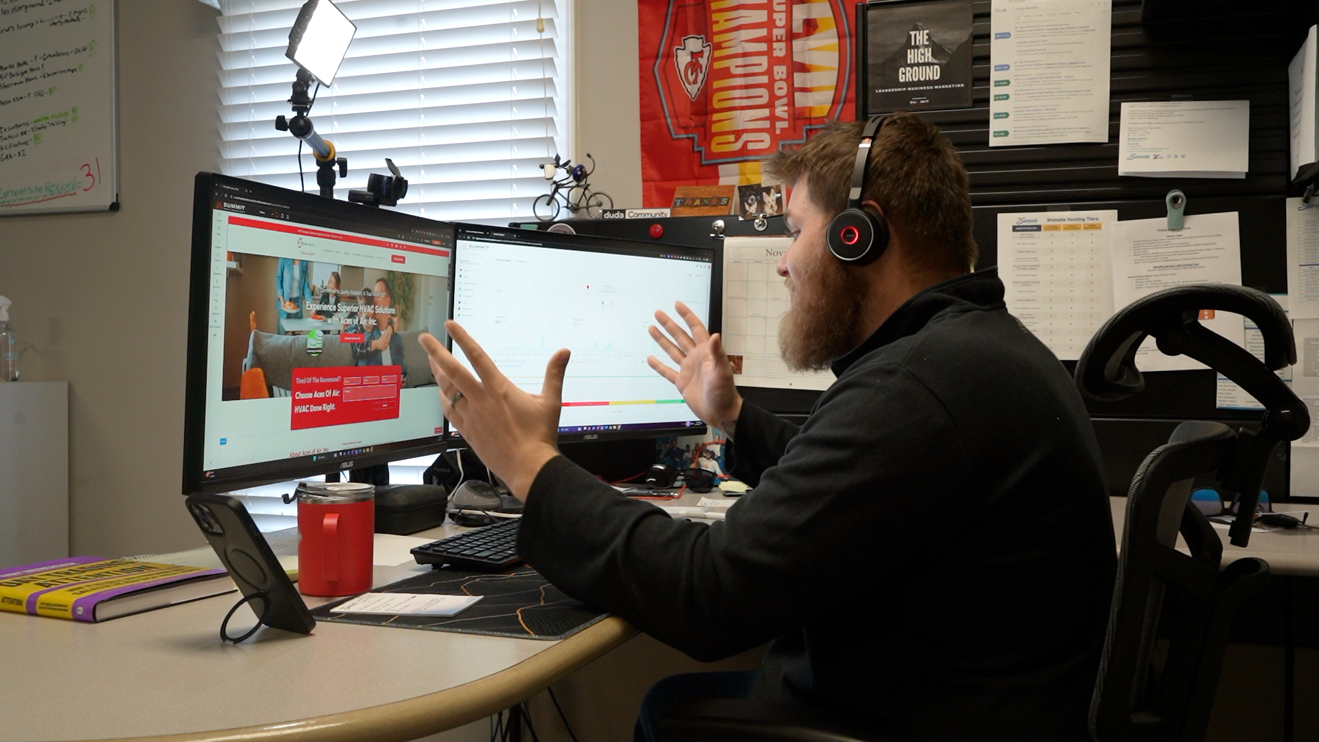 A man wearing headphones is sitting at a desk in front of two computer monitors.
