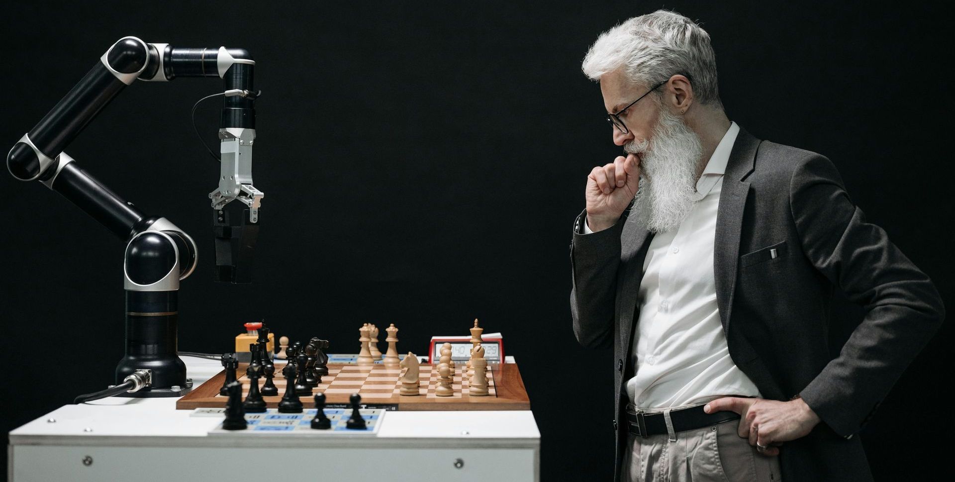 A man is playing chess with a robotic AI arm.