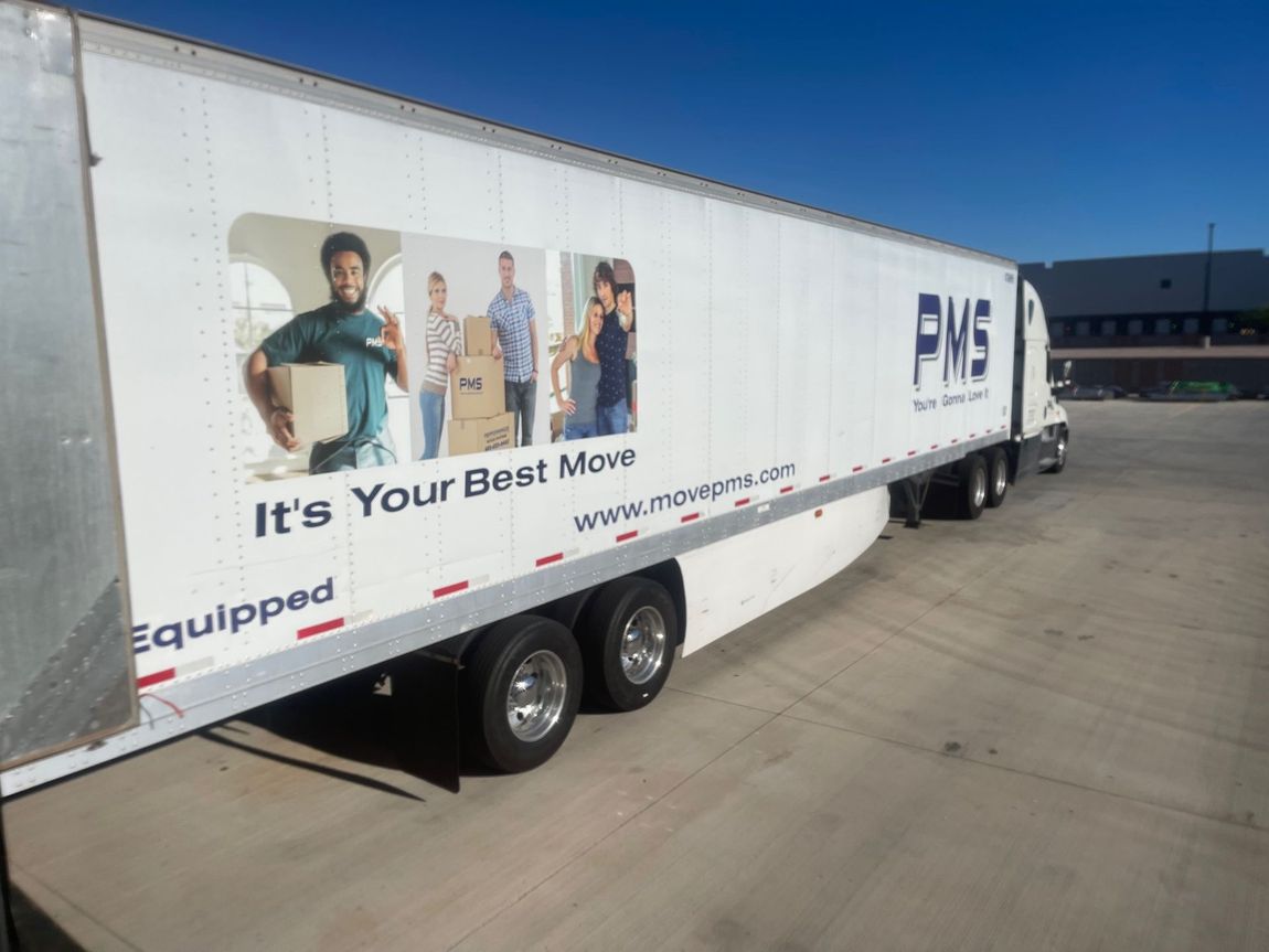 White PMS moving truck with family graphic, blue sky, and text 