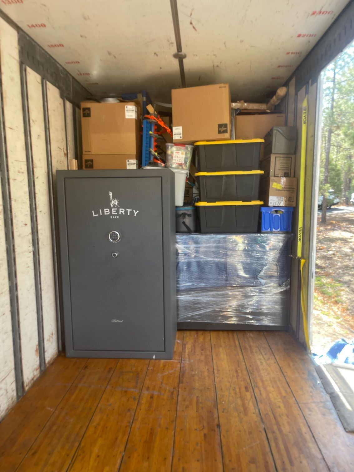A Liberty gun safe inside a cargo container, surrounded by boxes and other packed items.